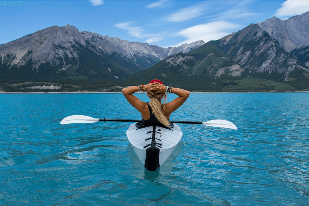 Person kayaking on a lake with mountains in background